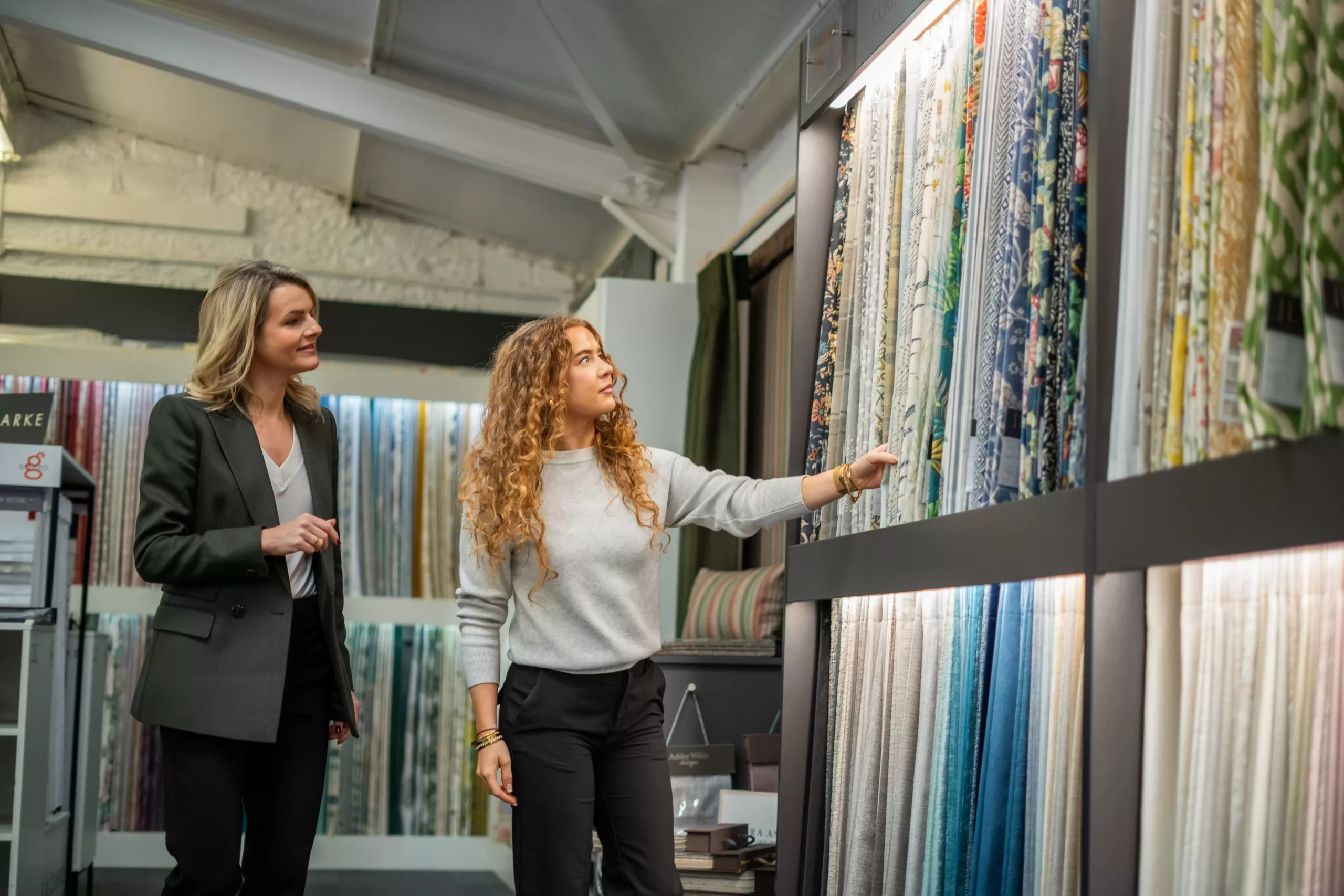 Two Curtain Studio staff members browsing fabrics for curtains.
