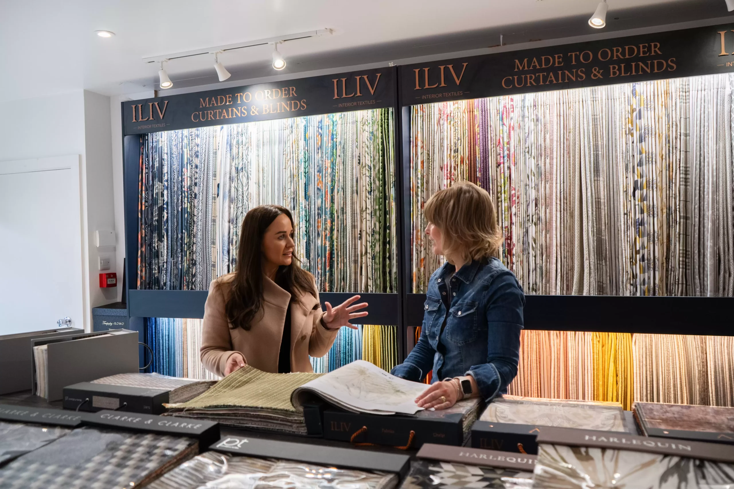 Two people discussing fabric options for curtains.