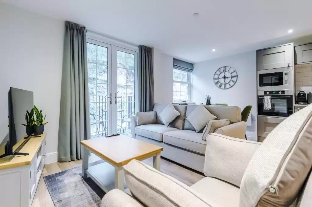 A neutral-coloured lounge room featuring desaturated green accents in the form of blinds and curtains.