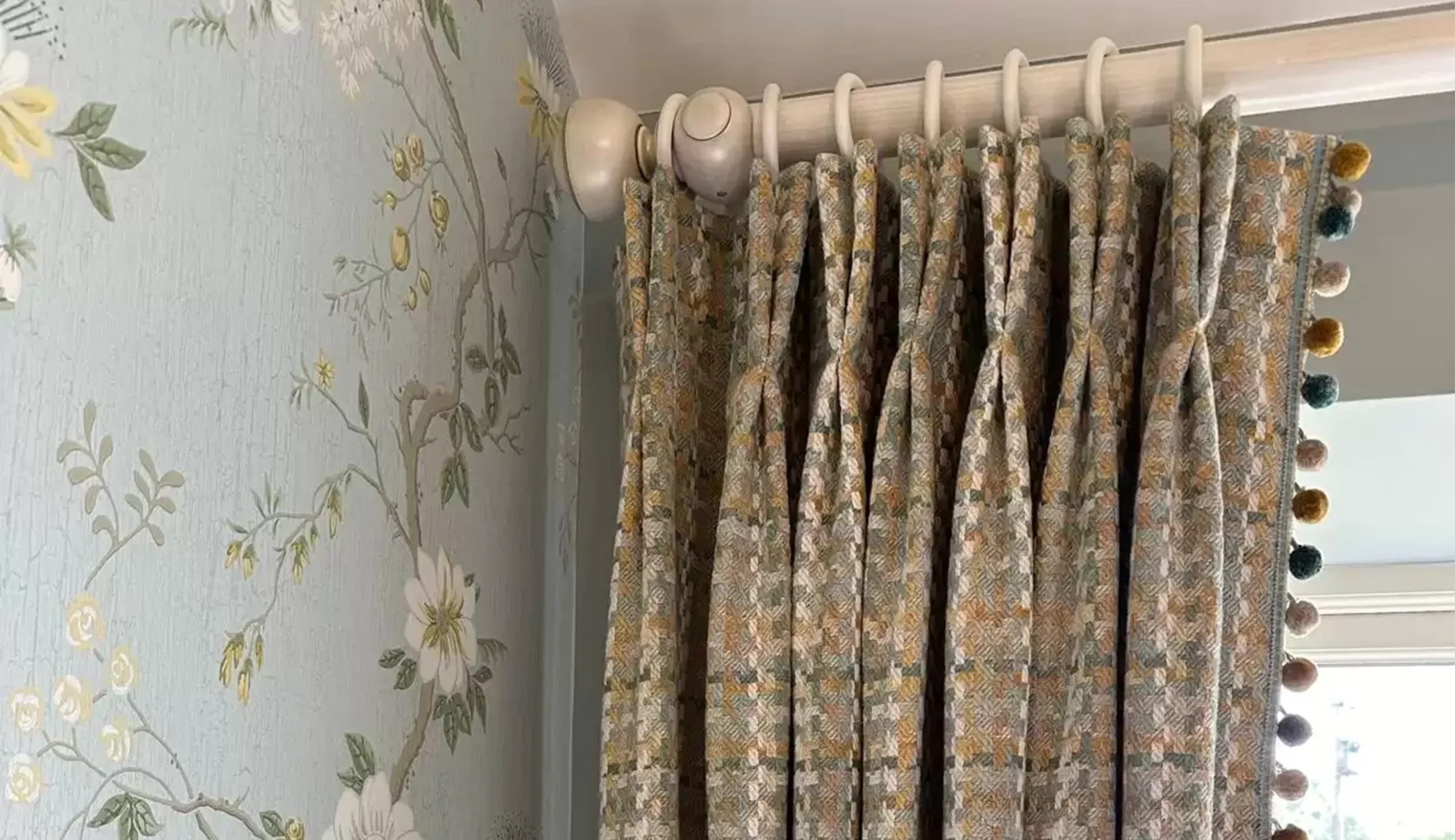 A close up of grey and mustard patterned curtain with accents of white.