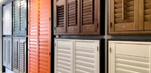 A collection of wood panel blinds in a showroom in various shades of white, cream and brown.