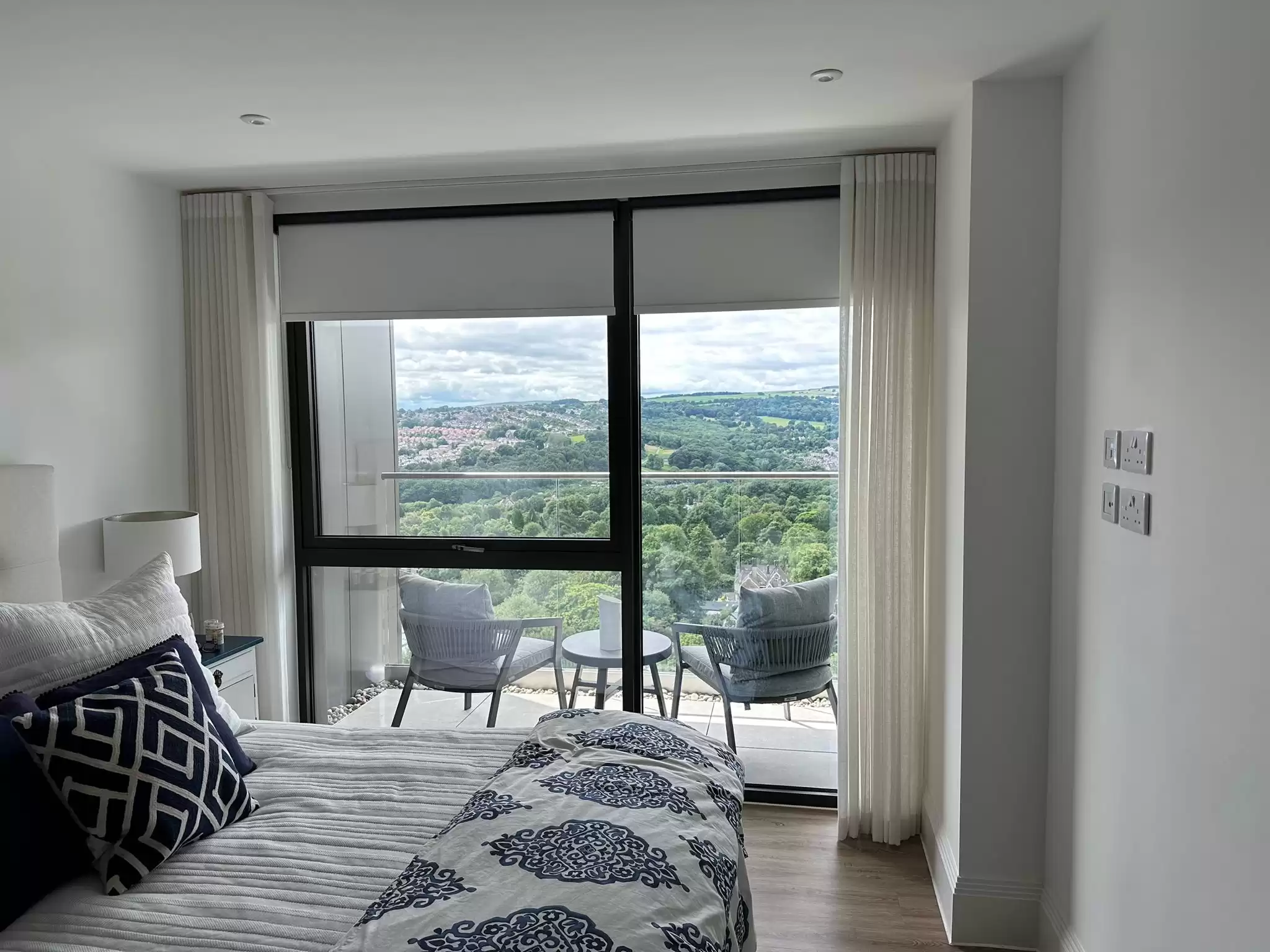 A floor to ceiling window with both blinds and curtains covering it.