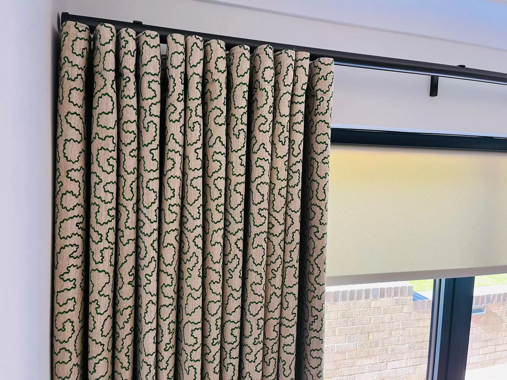 A close-up of a beige curtain with green patterns decorating it.