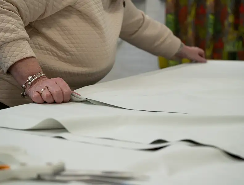 A woman lining up fabric to be measured.